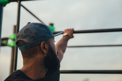 Man wearing a ball cap grabbing a workout bar